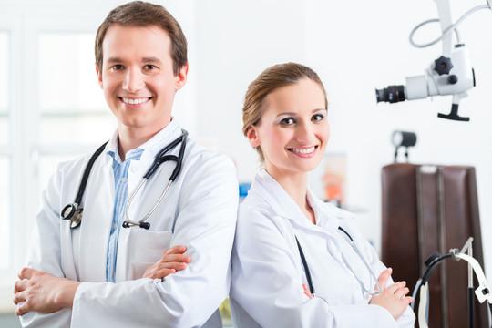 医生-男性和女性，站在诊所或医生办公室用听诊器