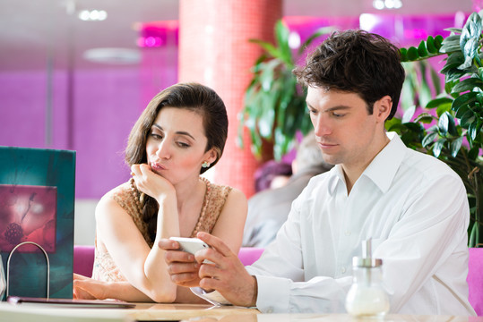 夫妻俩在一家咖啡馆共度闲暇时光，她很生气，因为他在电话里表现得很忙