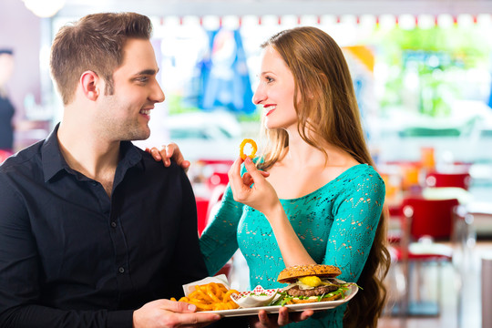 朋友或夫妇在美国快餐店吃带汉堡和薯条的快餐