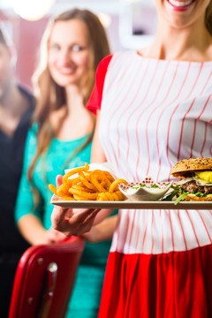 朋友或情侣在美国快餐店吃快餐，女服务员穿着短装上菜