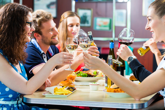 朋友或夫妇在美国快餐店吃快餐，喝啤酒和葡萄酒