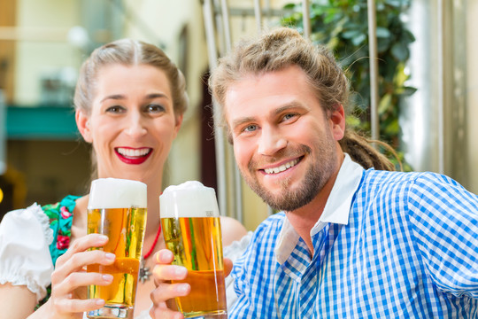 年轻夫妇在传统的巴伐利亚小吃店或酒吧与啤酒