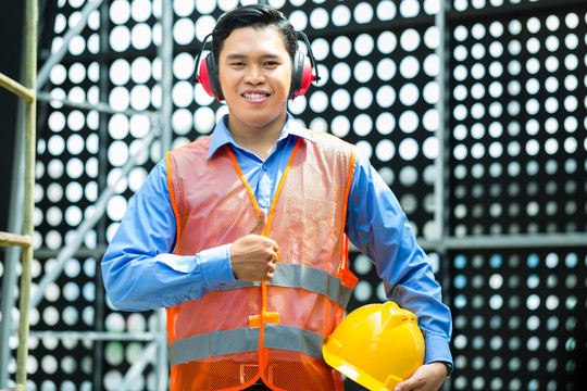 在亚洲的一个建筑工地上，戴着头盔和安全背心的亚裔印尼建筑工人