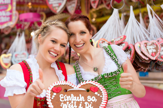 在节日或啤酒节上，穿着传统巴伐利亚服装的年轻女性（dirndl或tracht）拿着姜饼心形纪念品