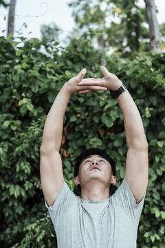 英俊的亚洲人做手臂伸展运动，运动前热身。