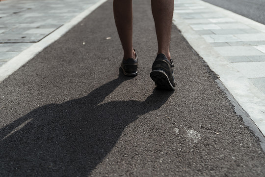 运动员在公路跑道上激情奔跑的双腿。