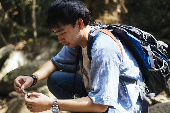 男性徒步旅行者坐在岩石上休息片刻。