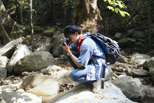 男性徒步旅行者坐在岩石上休息片刻，并为岩石拍照。