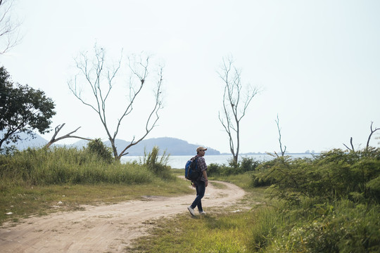 男性冒险家喜欢在阳光明媚的日子里走在自然小径上，用相机拍下大自然的照片。