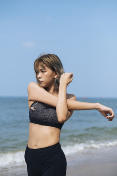 短发运动型女人在沙滩上伸展和做瑜伽。