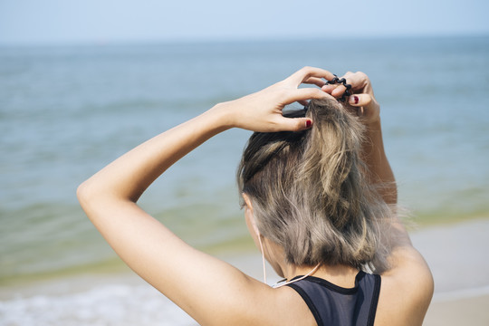短发运动型女子跑步前尽量把头发扎好准备，戴上运动内衣和耳机听音乐。