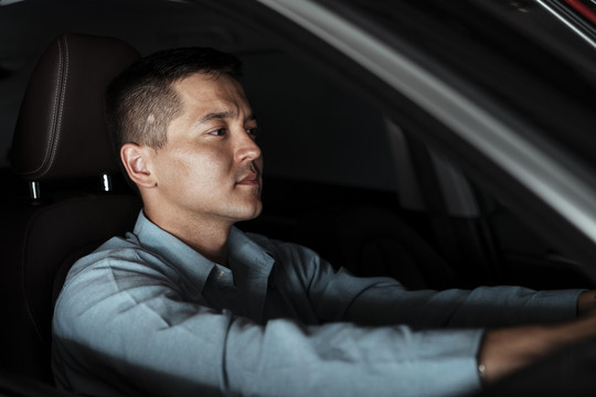 右图是一个穿着蓝色衬衫的商人坐在汽车的驾驶座上。