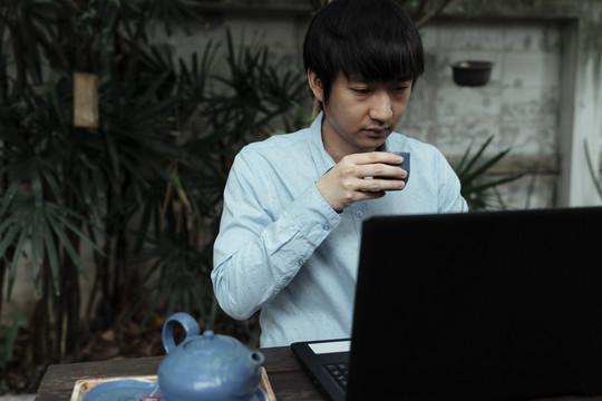 一个穿蓝衬衫的人拿着一壶茶在公园里工作。
