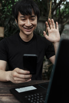 一个穿着黑色t恤衫的男人和一个让他开心和微笑的人打视频电话。
