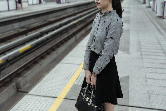 晚上，亚泰妇女拿着黑色袋子在月台上等火车。