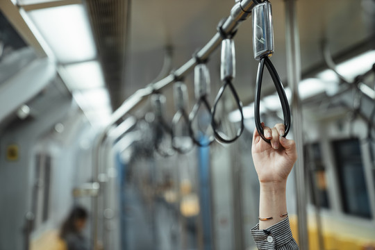 一个女人的手挂在火车里的带子上。