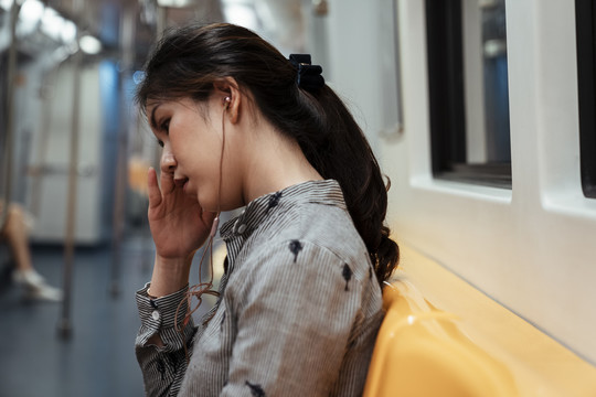 劳累的亚泰妇女，辛苦工作后头痛和偏头痛。坐在火车上的女上班族。不健康。