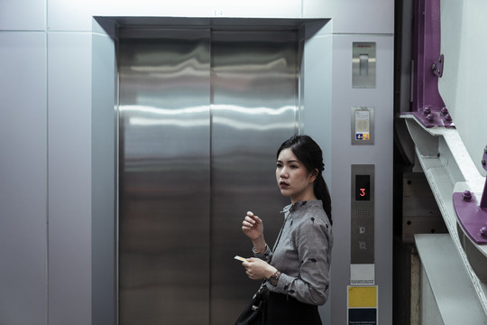 亚泰女子用智能手机等电梯。