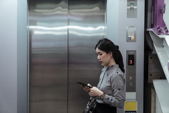 亚泰女子用智能手机等电梯。