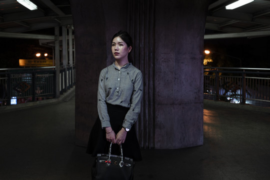 办公室亚泰女子独自一人站在曼谷市的夜晚。