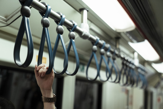 一个女人的手抓着火车里的带子。