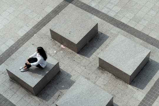 一位泰国妇女坐在广场的方石旁。