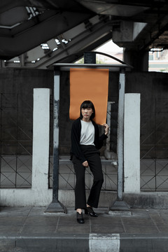 年轻的泰国亚裔女子深色短发站在街上橙色的空白纸上。