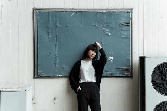 在废弃的学校里，时髦的亚泰年轻女子深色短发站在黑板或黑板上。