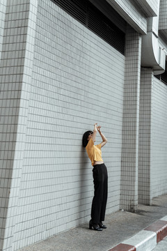 年轻的泰国亚裔女子深色短发穿着橙色衬衫站在街上。很酷的姿势。