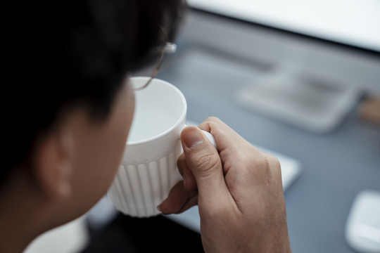 复制空间-男人头喝咖啡从一个白色的杯子在电脑前。
