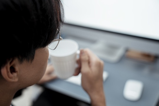 复制空间-男人头喝咖啡从一个白色的杯子在电脑前。