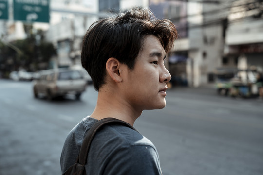 曼谷街头等待出租车的亚洲年轻帅哥侧视特写。