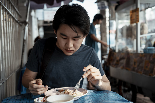 在曼谷吃鸡肉饭的亚洲游客。街上有泰国菜。