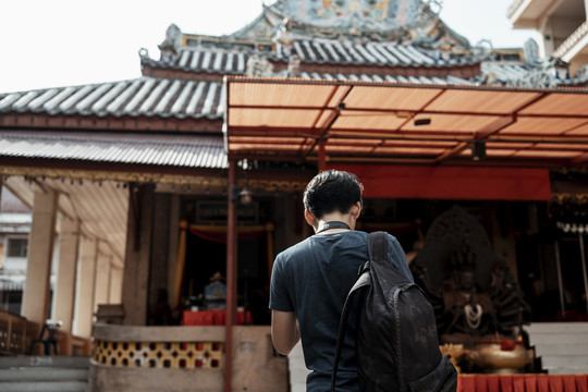 后景-年轻英俊的亚洲背包客在中国寺庙旅行。