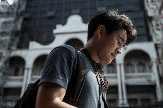 特写年轻英俊的亚洲背包客游客男子在城市旅行。