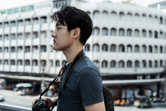 复制空间-年轻英俊的亚洲摄影师男子行走在曼谷市。