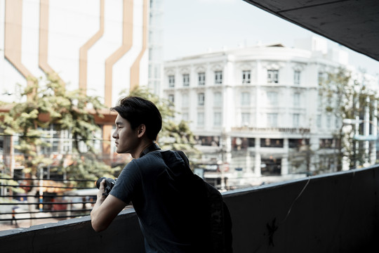 年轻英俊的亚洲摄影师看着街上的男人。