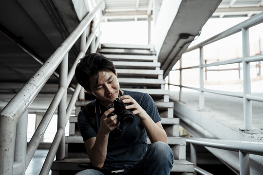 快乐的年轻英俊的亚洲摄影师看着镜头微笑。