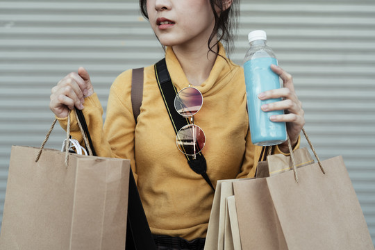 美丽可爱的亚洲女人拿着水塑料瓶和购物塑料袋。生态购物。