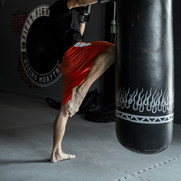 亚泰体育男子膝盖向上沙袋在健身房。自卫、拳击和训练概念。