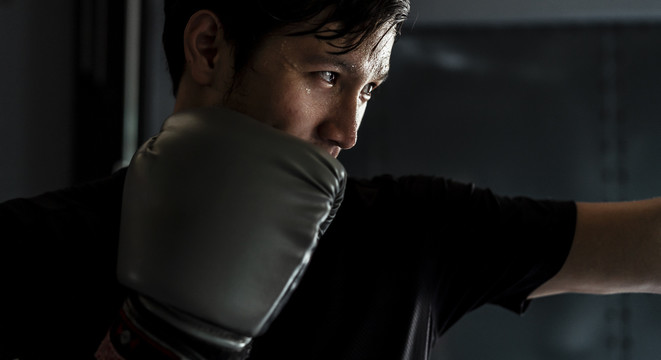 运动员亚泰体育男子戴黑色拳击手套戒备战斗。