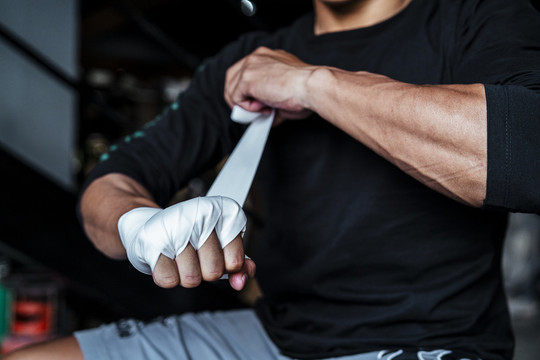运动员亚泰体育男子滚动拳击磁带周围的手。拳击手准备战斗。泰拳。