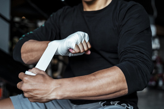运动员亚泰体育男子滚动拳击磁带周围的手。拳击手准备战斗。泰拳。