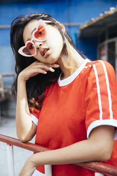 特写肖像-年轻迷人的亚泰女性深色头发，穿着红色衬衫，戴心形眼镜。