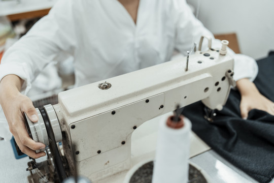 年轻的泰国设计师制衣妇女在白色缝纫机上工作。