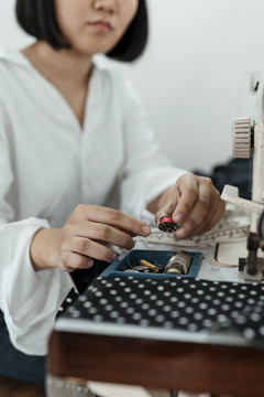 年轻的亚洲设计师在缝纫机站用红纱做布料。