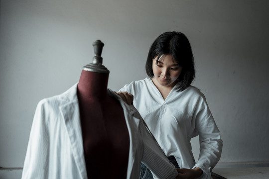 年轻的亚洲设计师在展厅里用卷尺测量布臂。