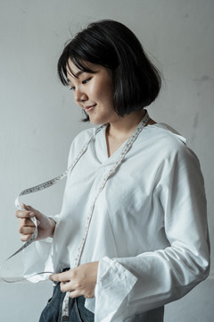 年轻的亚洲设计师短发女子拿着卷尺在展厅工作。