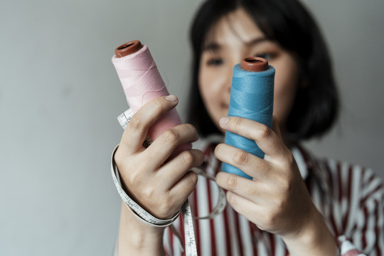 年轻的亚洲女设计师，在粉色和蓝色两种颜色中选择一种来做衣服。