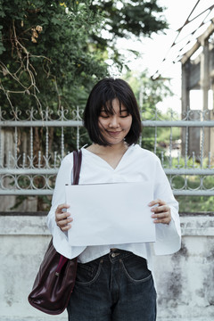 年轻的亚洲女设计师在街头展示纸牌。